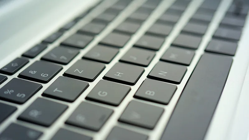 Close-up of hands typing on a laptop, sending an email with an attachment